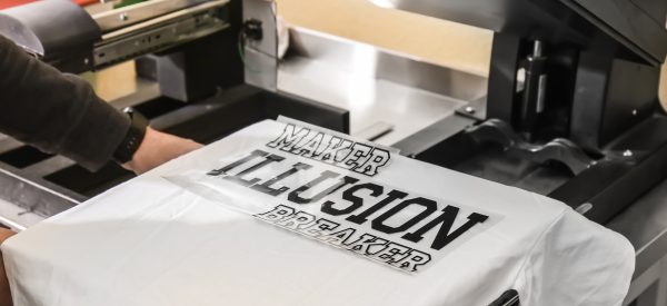 Young man printing on t-shirt at workshop